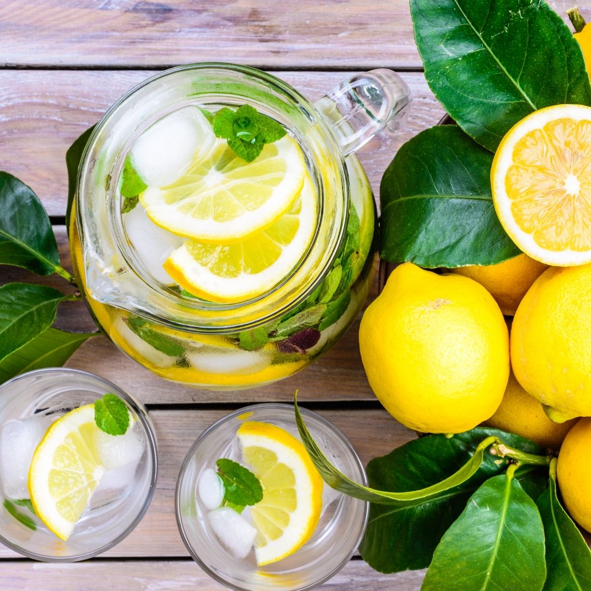 Benefits of lemon water when enjoyed daily like this fresh pitcher with lemons and greens.