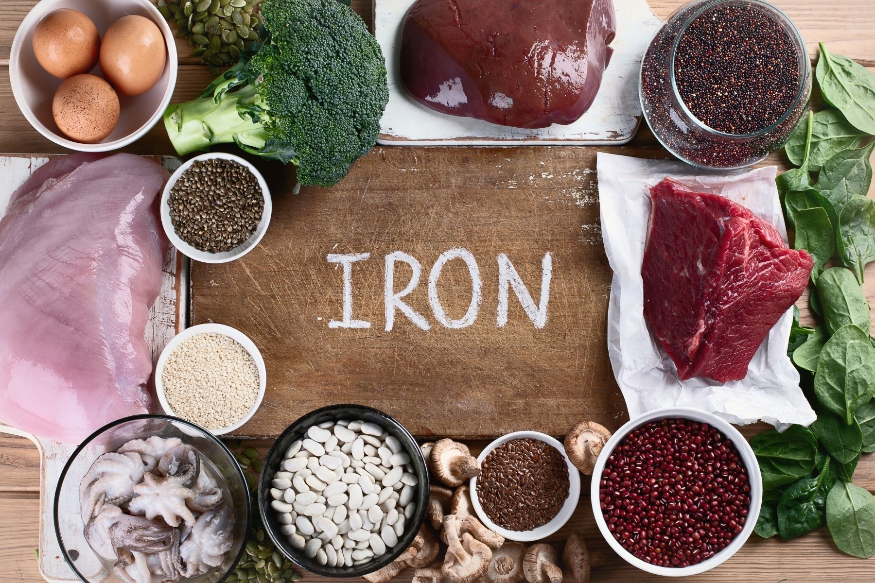 Foods that are rich in iron that you can add to your diet shown on wooden surface.